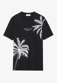 T-shirt en coton noir avec des graphiques de palmier blancs sur le côté gauche, avec le texte "PIER ONE BERLIN" centré au-dessus du design.