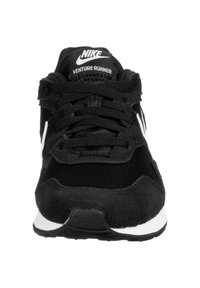 Black Nike Venture Runner sneakers with a mix of suede and mesh materials, featuring laces, a white logo, and a white midsole.