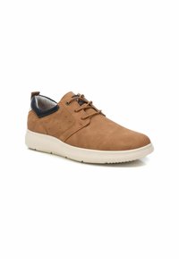 Zapatos de malla marrones con una textura suave, punta redondeada, acentos en azul marino contrastantes y suela clara con perforaciones detalladas.