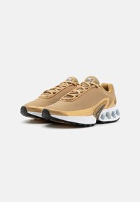 Tan athletic shoes with a mesh upper, textured surface, and padded collar. Features a white midsole and rubber outsole with visible air units.