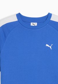 Mėlyna medvilninė marškinėliai su baltais akcentais ant pečių ir maža balta Puma logotipo etikete krūtinėje. Apvali iškirptė ir trumpomis rankovėmis.