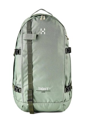 Mochila grande verde con correa vertical, hebillas laterales, asa superior y texto "TIGHT™ LARGE" en el panel frontal.
