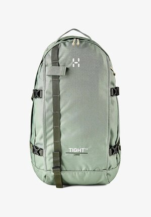 Mochila grande verde con correa vertical, hebillas laterales, asa superior y texto "TIGHT™ LARGE" en el panel frontal.