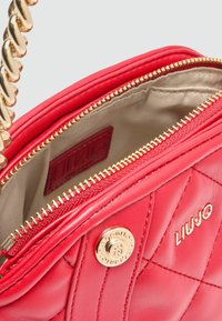 Rote gesteppte Handtasche aus glattem Leder mit goldfarbenem Reißverschluss und Kettenriemen. Verfügt über ein Innenfutter und ein Markenlogo-Detail.