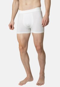 Boxers pour hommes blancs en tissu extensible, dotés d'une taille lisse, d'une coupe ajustée et d'un design sans couture pour plus de confort.