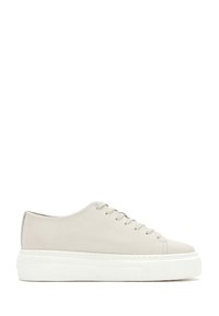 Beige leren sneaker met lage schacht, dikke witte plateauzool en bijpassende beige veters, zijaanzicht op witte achtergrond.