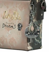 Tasche in Braun- und Grüntönen mit einem gemusterten Design und dekorativen Nähten, "AneLke"-Logo und einem silbernen Charm mit Tropfen- und Mondmotiv.
