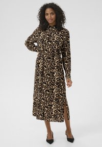 Abito camicia con stampa leopardata nei toni del marrone e del nero, con colletto, maniche lunghe e vita regolabile con coulisse. Presenta uno spacco laterale e un tessuto morbido.