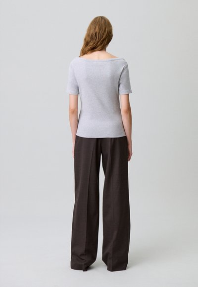 Top grigio a maniche corte con scollatura ampia, abbinato a pantaloni larghi di colore marrone scuro. Tessuto morbido, vestibilità rilassata e design minimalista.