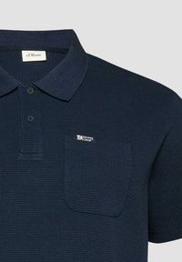 Polo bleu marine texturé avec patte de boutonnage à deux boutons, poche poitrine étiquetée "s.Oliver Elevated Casual" et col classique.