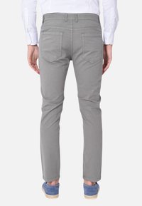 Pantaloni in cotone grigi con vestibilità slim, caratterizzati da dettagli di cucitura discreti e doppie tasche posteriori, abbinati a scarpe casual blu.
