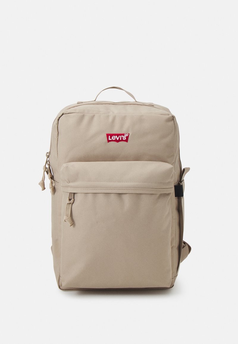 Sac à dos en toile beige avec le logo rouge de Levi's, poignée supérieure, poche avant zippée, bretelles rembourrées et fermetures éclair durables. Forme rectangulaire.