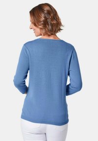 Hellblauer, langärmeliger Pullover mit rundem Ausschnitt, glatter Stricktextur und geripptem Saum. Keine sichtbaren Muster oder Beschläge.