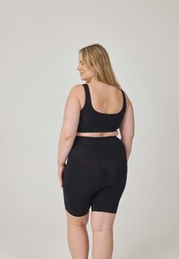 Czarny komplet odzieży sportowej z dopasowanym biustonoszem na szerokich ramiączkach oraz wysokim stanem krótkich spodenek rowerowych, wykonany z gładkiego, elastycznego materiału.
