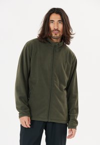 Chaqueta de forro polar en verde oscuro, con un alto cuello, cremallera completa y bolsillos laterales con cremallera; textura suave con un discreto detalle de logo.