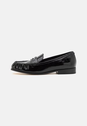 Czarne lakierowane penny loafersy z niskim obcasem, przeszyciem typu moc toe oraz detalem paskowym na neutralnym tle.