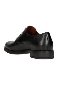 Scarpa in pelle nera con punta tonda, superficie texturizzata, tacco basso e interno rosso a contrasto. Presenta una chiusura discreta sul collo.