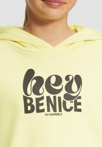 Gelb Hoodie mit einem großen schwarzen Grafiktext, der "hey BENICE TO YOURSELF" sagt. Weicher Stoff mit einem lässigen Design und Kapuze.