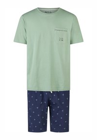 Green cotton t-shirt with a chest pocket, paired with navy shorts featuring a small palm tree pattern in blue. Both items are casual wear.