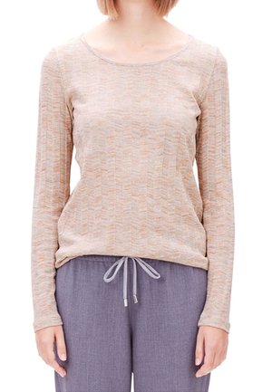 Beige langmouwtop met een getextureerd zigzagpatroon, ronde halslijn; gecombineerd met grijze broek met trekkoord voor een relaxte pasvorm.