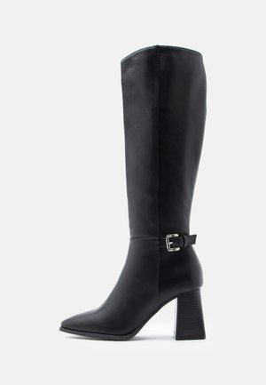 Black knee-high boot made of smooth leather, featuring a pointed toe and a chunky heel with a buckle accent on the ankle strap.