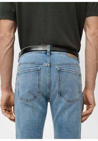 Vaaleansiniset farkut, joissa on vartalonmyötäinen leikkaus, kaksi takataskua ja musta nahkainen vyö. Kangas on sileäpintainen.