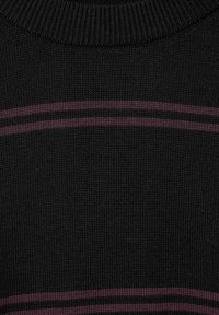 Svart stickad tröja med rund halsringning, med en framträdande horisontell vinröd rand nära botten. Texturen verkar slät och tät.