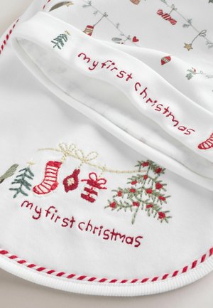 Hvid bomuldsforklæde med rød og grøn broderi, der står "min første jul", med festlige mønstre som træer, strømper og gaver.