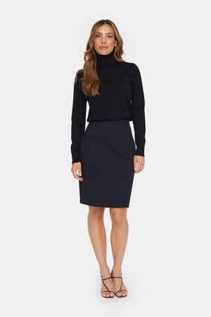 Zwarte coltrui gecombineerd met een donkere potloodrok. De outfit heeft een getailleerde pasvorm en een zachte stoftextuur. Simpele sandaaltjes met hak.