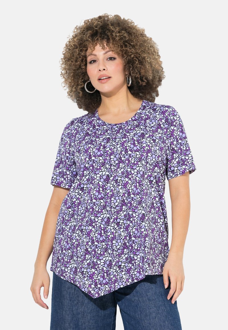 Kortärmad lila topp med ett geometriskt mönster i vitt och ljust lila, med rundad halsringning och asymmetrisk fåll.