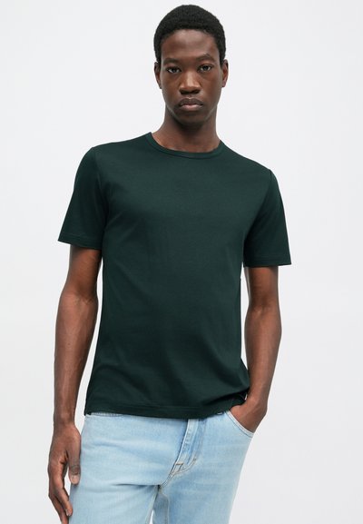 Σκούρο πράσινο κοντομάνικο μπλουζάκι από βαμβάκι με στρογγυλή λαιμόκοψη. Εφαρμοστή σχεδίαση, ομαλή υφή και διακριτές λεπτομέρειες ραφής.