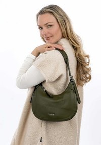Borsa a tracolla in pelle verde con forma arrotondata e finitura testurizzata, dotata di chiusura con zip e tracolla regolabile. Nome del marchio visibile sulla parte anteriore.