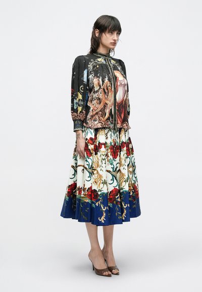 Langes, fließendes Kleid mit einem schwarzen, gemusterten Oberteil und einem floralen, mehrfarbigen Rock mit Rosen und dekorativen Wirbeln.