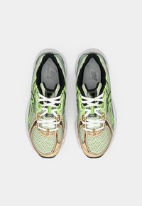 Lichtgroene mesh hardloopschoenen met zwarte accenten, voorzien van witte veters en een doorzichtige zool. Opvallende zijbranding en gedetailleerde stitches.