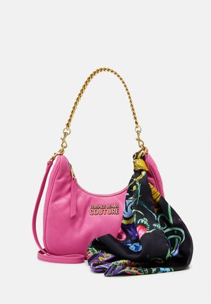 Sac à main en simili cuir rose matelassé avec une chaîne dorée et une écharpe à motif noir attachée, arborant des motifs floraux et abstraits vibrants.