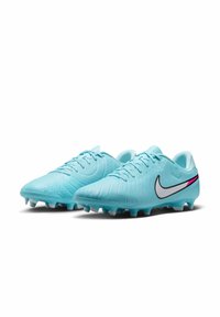 Világoskék focicipők texturált felülettel, kiemelkedő fekete-fehér Nike logóval és rózsaszín díszítéssel az oldalon.