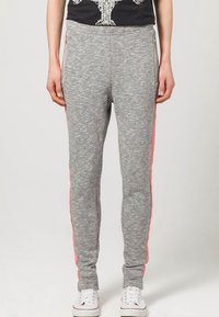 Graue Jogginghosen mit weicher Textur, ausgestattet mit rosa Seitenstreifen und Reißverschlusstaschen. Taillierter Schnitt und elastischer Bund für zusätzlichen Komfort.