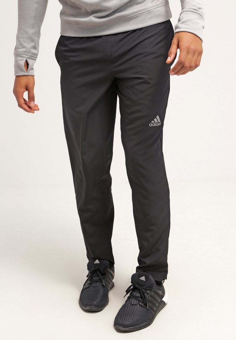 Černé sportovní kalhoty vyrobené z lehkého materiálu, s úzkým střihem a vyšitým logem Adidas na levém stehně.