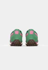 Scarpe sportive in suede verde con accenti rosa, caratterizzate da un retro arrotondato, suola in brown testurizzata e logo sul tallone.