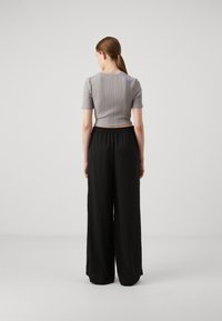 Grey ribbed short-sleeve top paired with black wide-leg pants, featuring an elastic waistband, smooth texture, and flowing design.