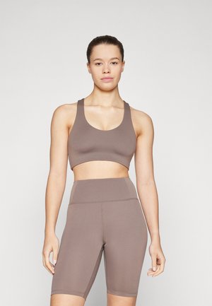 Brun sports-bh og høytåndte shorts-sett. Laget av glatt, elastisk materiale. Har rund halslinning og brede stropper.