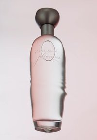 Botella de perfume de vidrio transparente con un tapón oscuro y redondeado. La botella tiene una forma suave y contorneada, con un sutil tono rosa y texto grabado.
