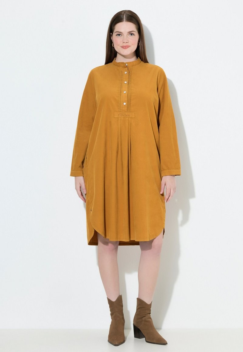 Senfgelbes, langärmliges Kleid mit rundem Halsausschnitt, Knopfleiste und gerafftem Rock. Aus weichem Stoff gefertigt, mit Seitentaschen versehen.