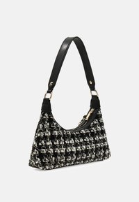Tweed handtas in zwart en wit met een gebogen vorm, aangevuld met een soepele zwarte leren schouderriem en gouden hardware accenten.