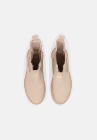 Beige kotníkové boty s hladkým koženým povrchem, elastickými bočními panely a zaoblenými špičkami. Podšité měkkým materiálem pro pohodlí.