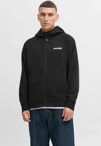 Zwarte zip-up hoodie met ribgebreide accenten, voorzakken en logo. Gemaakt van zachte stof, met een capuchon met trekkoord en een ontspannen pasvorm.