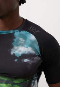 Black athletic shirt with colorful cloud patterns in teal, blue, and green. Features a fitted design and a logo on the shoulder.