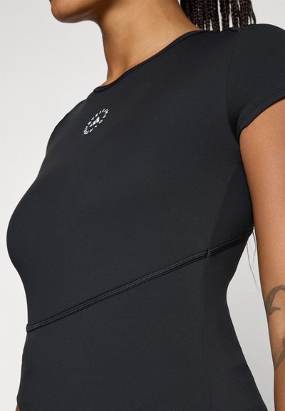 Top sportivo nero aderente realizzato in tessuto liscio ed elastico con maniche corte. Presenta un piccolo logo e dettagli di cucitura a contrasto.