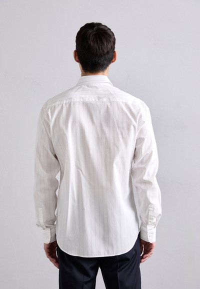 Camisa blanca de manga larga con rayas verticales, hecha de una tela suave. Presenta un corte recto, puños abotonados y un cuello clásico.