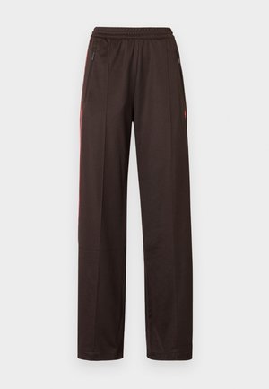Pantalon de sport noir avec une ceinture élastique, des poches latérales zippées et des bandes accentuées rouges le long des côtés ; matériau lisse et léger.